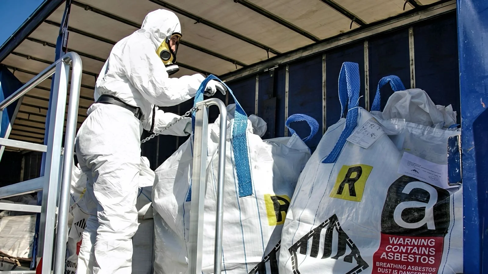Asbestos disposal specialist loading legally labelled, double-bagged asbestos waste for a licensed Surrey facility.
