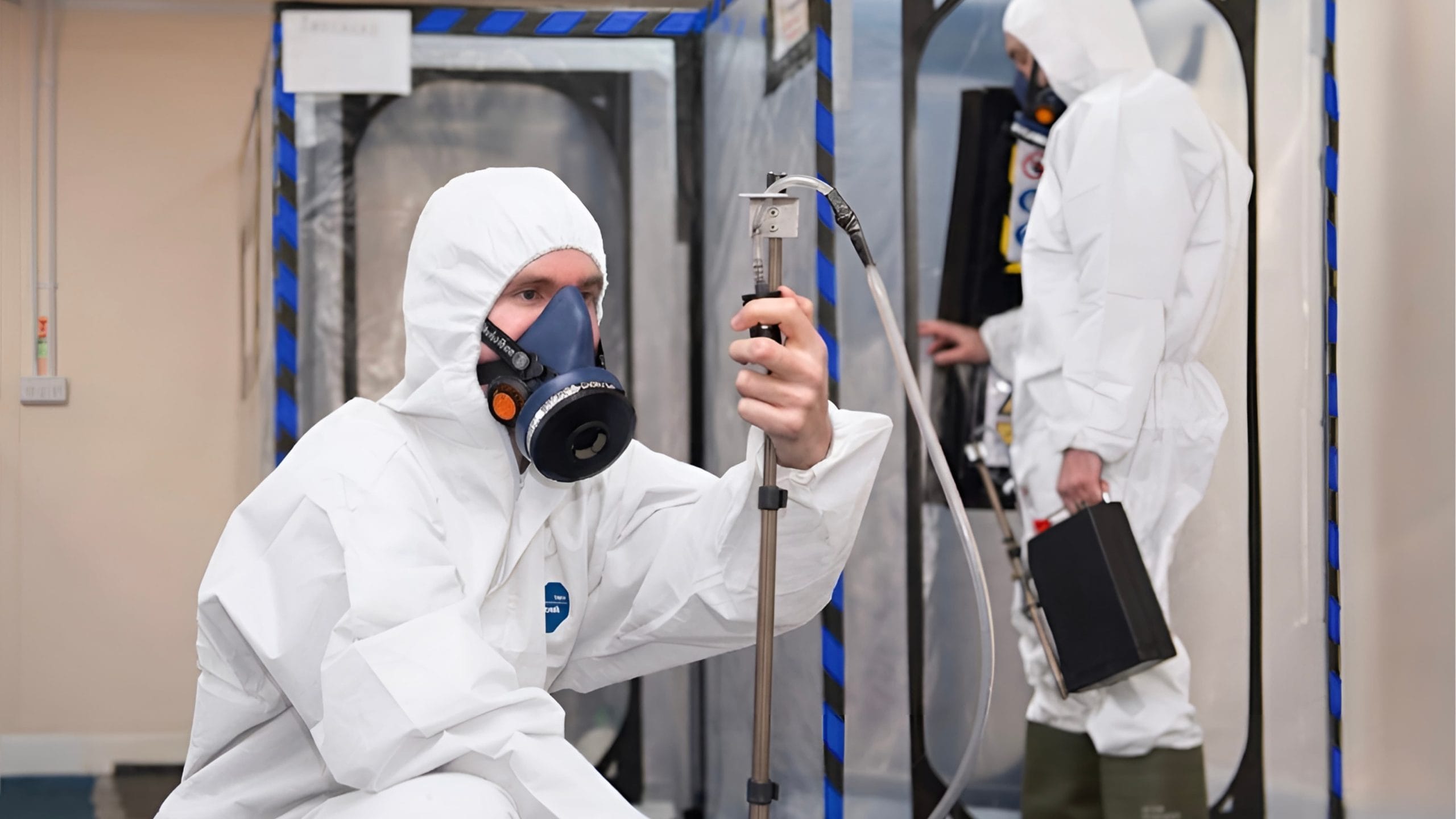 UKAS-accredited analyst carrying out independent asbestos air monitoring and clearance testing inside a sealed enclosure in Surrey