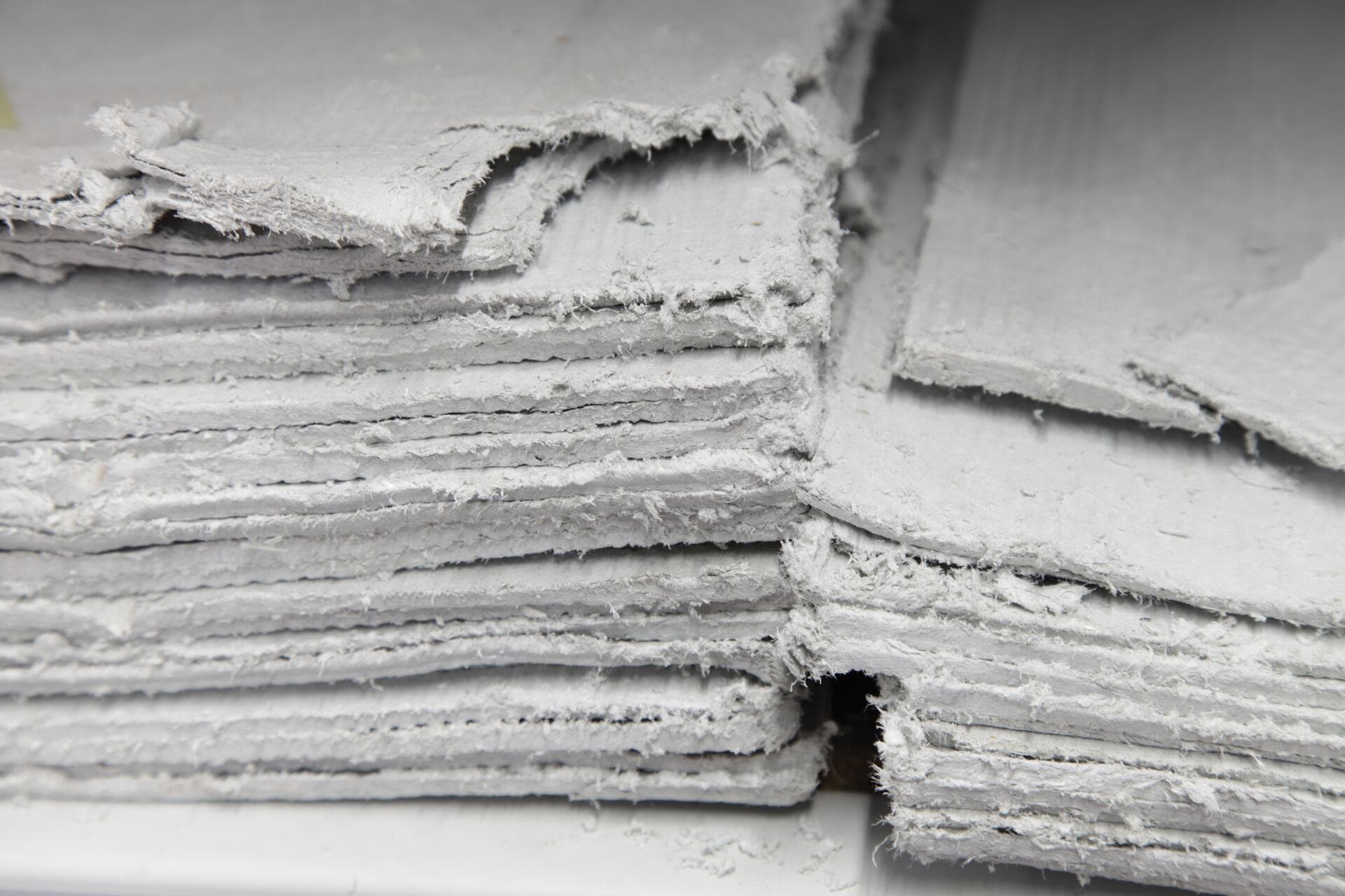 Close-up of stacked degraded asbestos cement sheets removed from a Surrey property awaiting licensed disposal