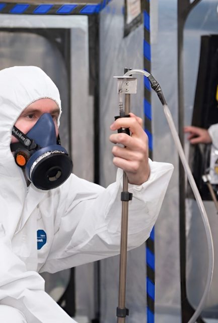 UKAS-accredited analyst carrying out independent asbestos air monitoring and clearance testing inside a sealed enclosure in Surrey