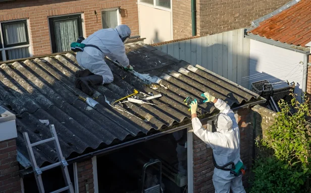UKATA-trained operatives in full PPE carefully dismantling an asbestos cement shed roof in a Surrey residential property