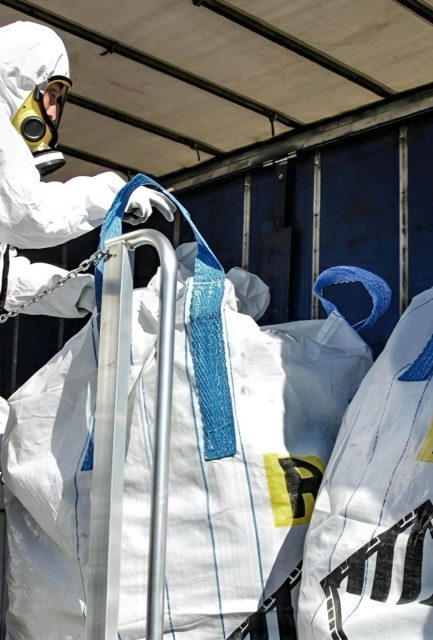 UKATA-trained operative in full PPE loading compliant asbestos waste bags onto a licensed collection vehicle for disposal in Surrey